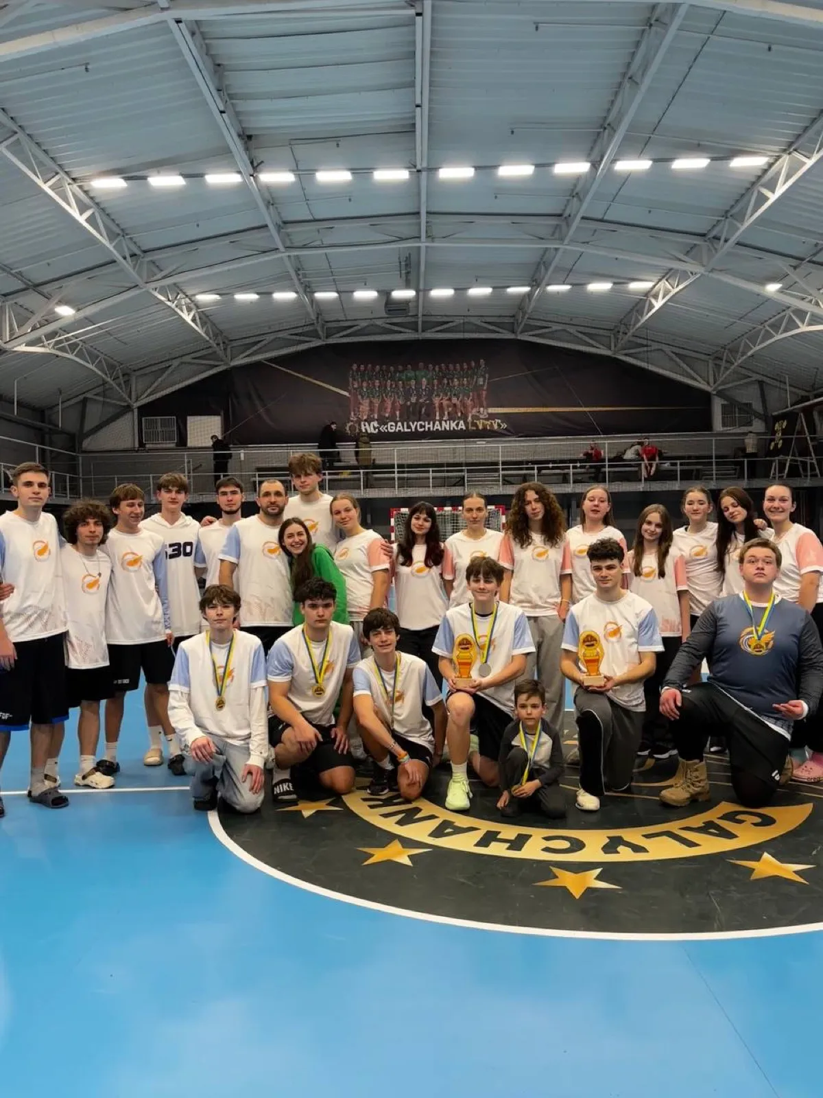 A large group of players with medals on the court.