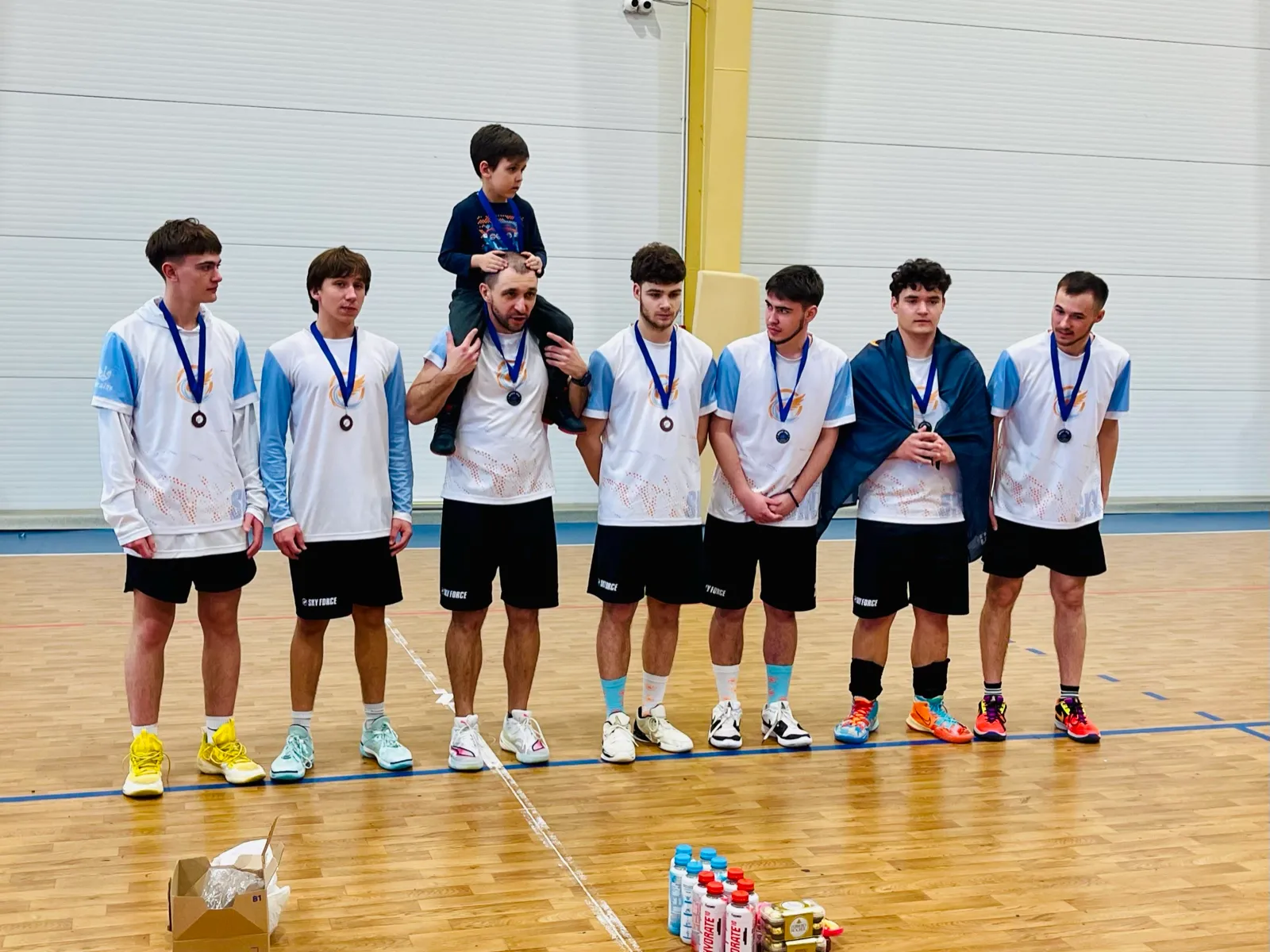 Boys with medals, a child on the coach’s shoulders.
