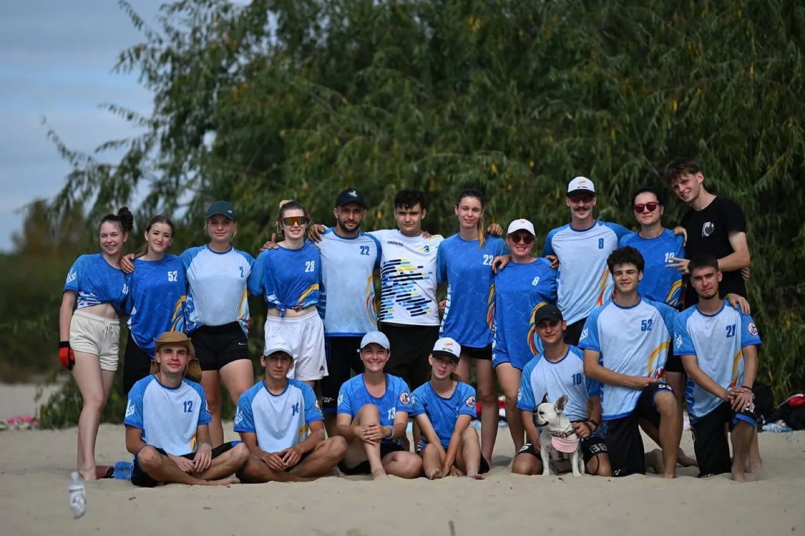 Team photo on a sandy beach at sunset.